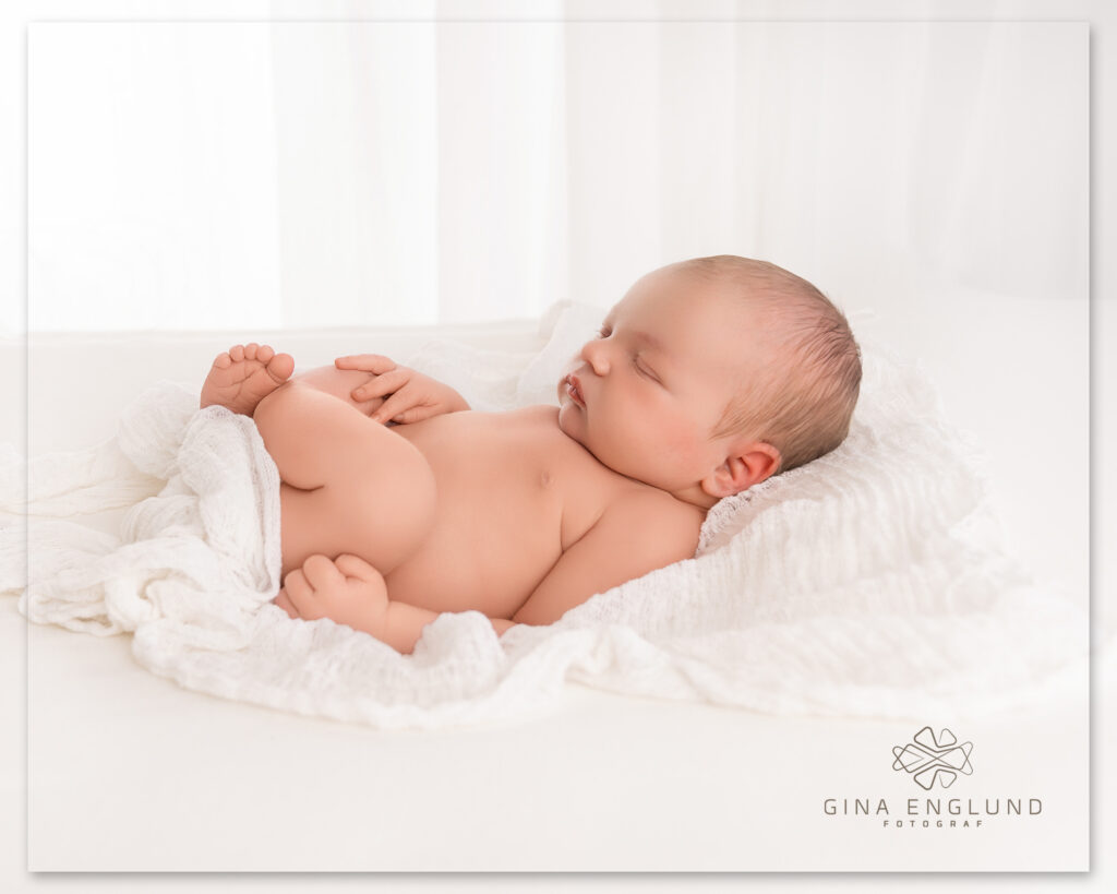 Sovende nyfødt baby på hvitt teppe fotografert i lyst studio på Sofiemyr