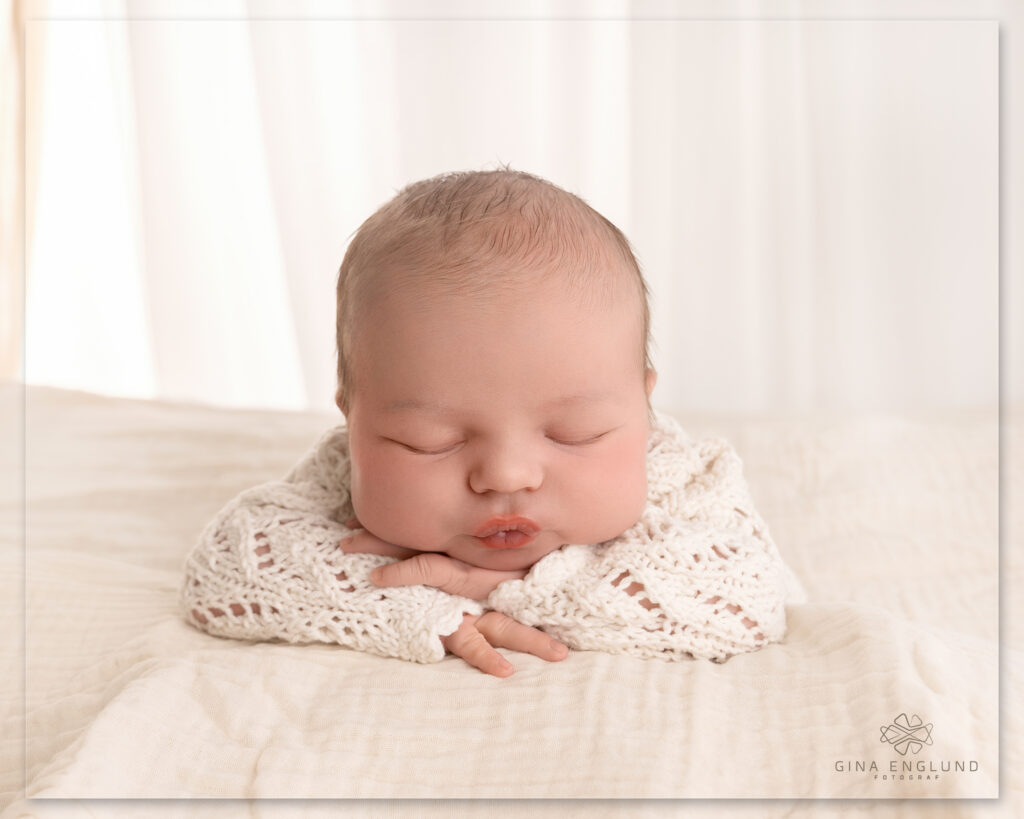 Nyfødt baby med hvit strikkegenser fotografert i studio på Sofiemyr nær Oslo