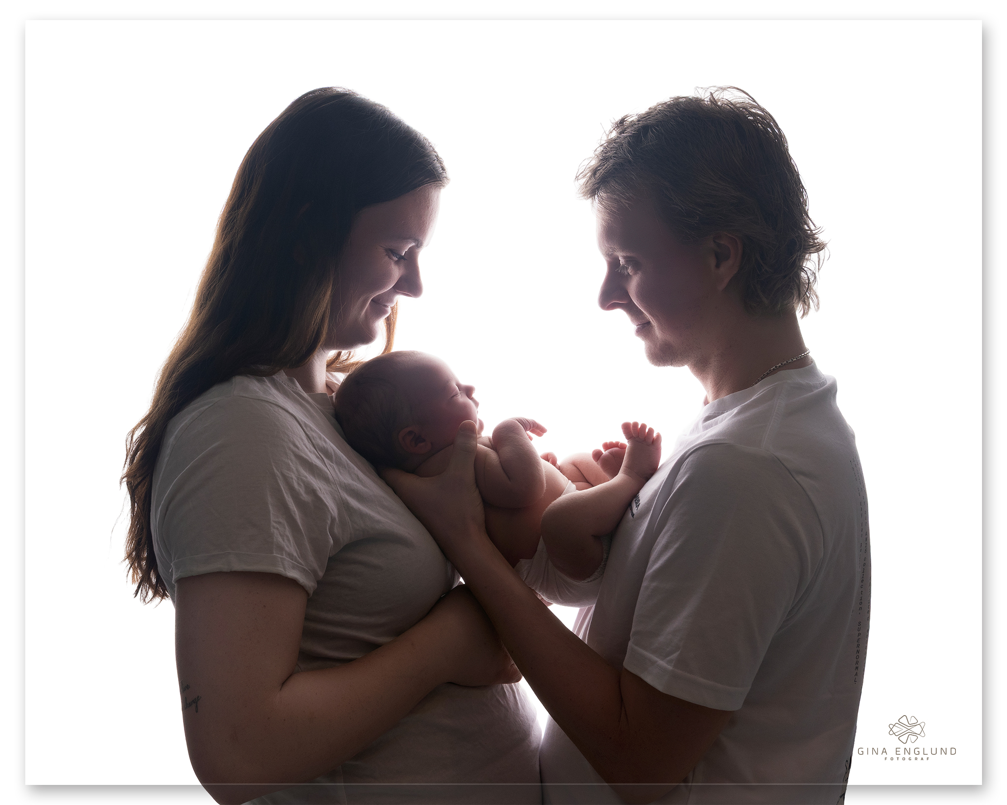 Nyfødt baby holdes kjærlighetsfullt av mamma og pappa under nyfødtfotografering i studio på Sofiemyr