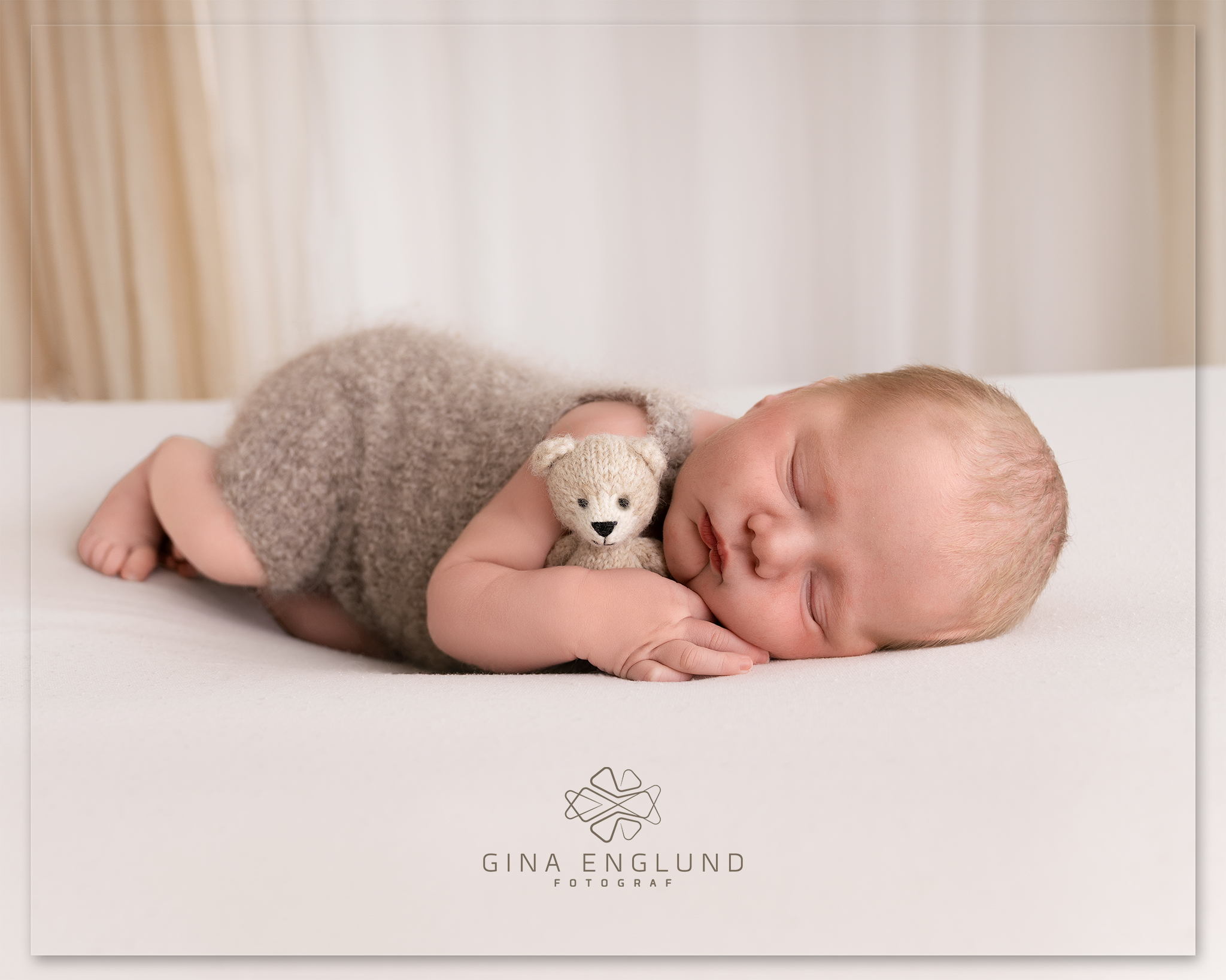 Nyfødt baby sover rolig på magen med en liten strikket bamse under nyfødtfotografering i studio på Sofiemyr.